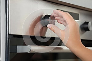 Woman regulating cooking mode on oven panel