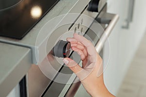 Woman regulating cooking mode on oven panel