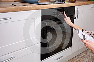 Woman regulating cooking mode on oven panel