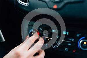 Woman regulating temperature on car air condition.