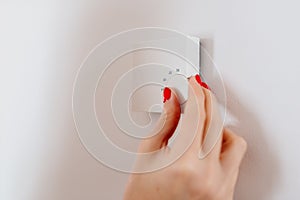 Woman regulating temperature on home heating thermostat