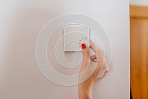 Woman regulating temperature on home heating thermostat