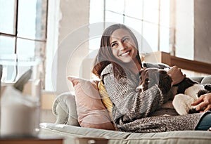 Woman relax on couch with dog, smile and content at home with pet and happy together with peace in living room