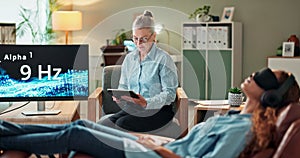 Woman, relax and headphones with therapist for sound frequency, noise or comfort lying on chair at clinic. Female person