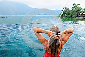 Woman relax in hot spring infinity pool with lake view