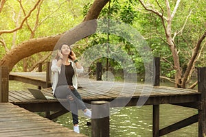 Woman relax and reading a book while listening music with headphone and laptop in the nature green park, girl happy.