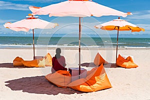 Woman relax on seat under parasol on summer beach