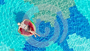 Woman relaxes in a big pool, floating on a ring.