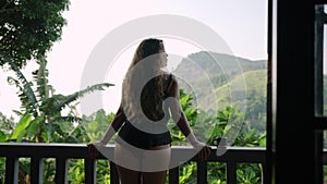 Woman relaxes on resort terrace with view of Ella Rock, sips tea. Traveller enjoys serene landscape morning, luxury