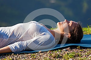 Woman relaxes in yoga asana Savasana outdoors