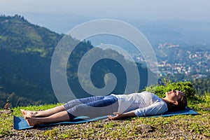 Woman relaxes in yoga asana Savasana outdoors photo