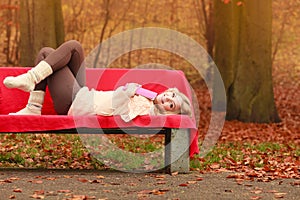 Woman relaxing in autumn fall park with book.