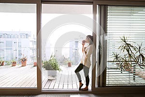 Woman relaxing on balcony holding cup of coffee or tea