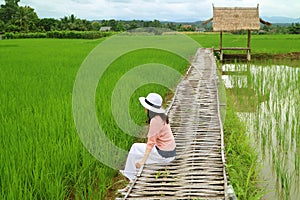 Woman Relaxing on the Bamboo Path over Vibrant Green Paddy Field, Nan Province, Northern Thailand