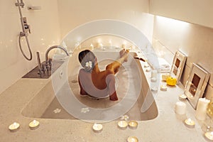Woman relaxing in bath with candles