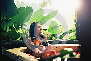 Woman relaxing bath with tropical flowers outdoor at luxury hotel