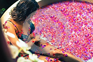 Woman relaxing bath with tropical flowers outdoor at luxury hotel