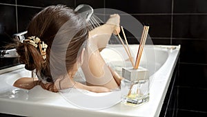 A woman relaxing in a bath and washing her legs with soothing foam. Importance of personal care and mental wellness