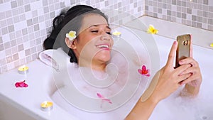Woman relaxing on bathtub with cellphone