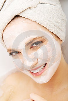 Woman relaxing in bathtub with face mask.