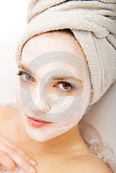 Woman relaxing in bathtub with face mask.