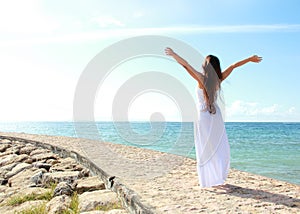 Woman relaxing at the beach with arms open enjoying her freedom