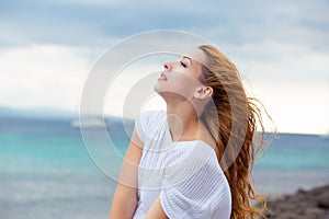 Woman relaxing at beach enjoying summer freedom with hair in the wind by the water seaside