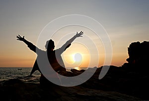 Woman relaxing at beach enjoying summer freedom with sunset in the sea