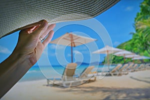 Woman Relaxing On Beach Holding Sun Hat and Sea in Background