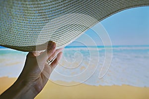 Woman Relaxing On Beach Holding Sun Hat and Sea in Background