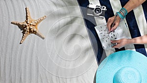 Woman relaxing on the beach and solving crosswords photo