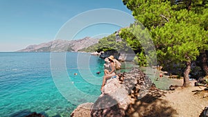 Woman relaxing on beach during summer vacation. Picturesque seaside, clarity of the Adriatic Sea meets leisurely comfort