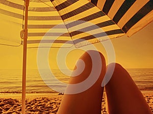 Woman relaxing on a beach with umbrella at romantic sunset sand sepia vintage retro coloring