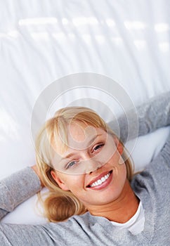 Woman relaxing on bed. Top view of pretty young woman lying on bed and smiling.