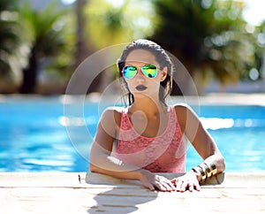 Woman relaxing in blue luxury swimming pool leisure on white natural stones