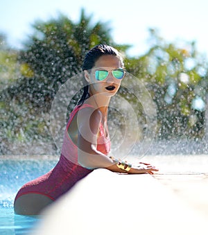 Woman relaxing in blue luxury swimming pool leisure on white natural stones vacation holidays