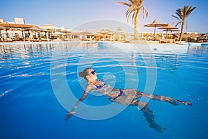 Woman relaxing in blue swimming pool