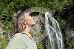 Woman relaxing breathing fresh air in a waterfall