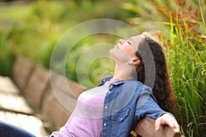 Woman relaxing breathing sitting on bench in a park