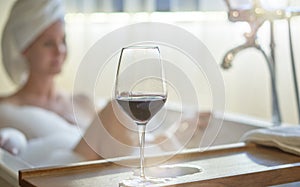 Woman relaxing in bubble bath in bathtub drinking wine