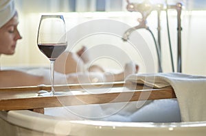 Woman relaxing in bubble bath in bathtub drinking wine