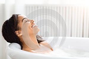 Woman relaxing in a bubble bath and smiling