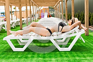 Woman relaxing in chaise lounge at the poolside. Summer relax