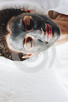 Woman relaxing with a charcoal facial mask