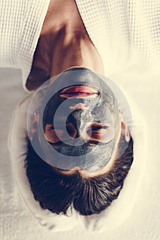 Woman relaxing with a charcoal facial mask