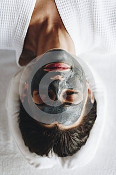 Woman relaxing with a charcoal facial mask