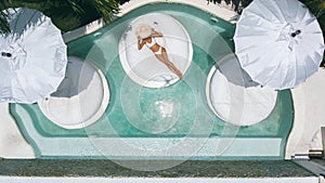 Woman relaxing in clear pool water in hot sunny day on Bali villa
