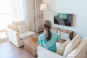 Woman relaxing on the couch, Girl using remote control and choosing TV show and movie series during rest on sofa in the morning.