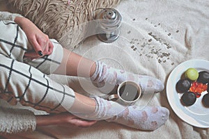 Woman relaxing in cozy place with sweets and a cup of tea.