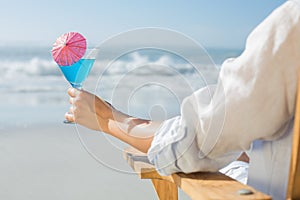 Woman relaxing in deck chair by the sea holding cocktail